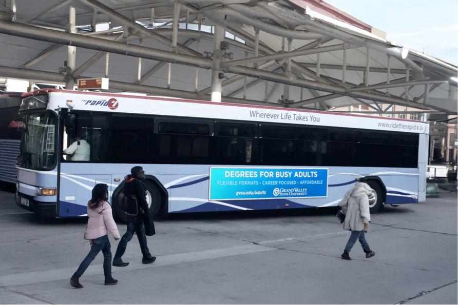 Pedestrians passing a bus with a commercial advertisement on its side